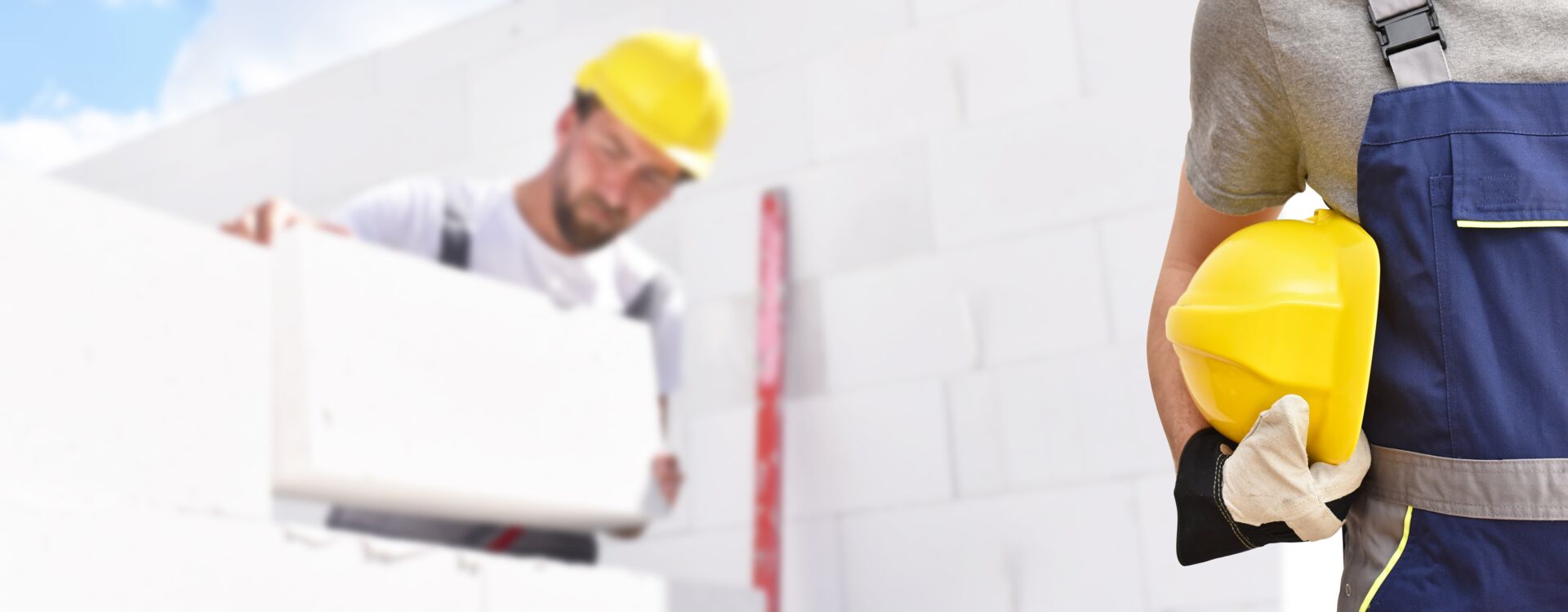 Zwei Bauarbeiter mit Schutzhelmen arbeiten auf einer Baustelle zusammen